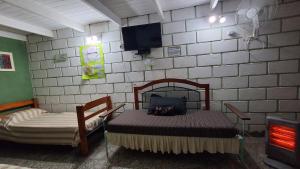 a bedroom with two beds and a tv on a wall at BelDaMar in Capilla del Monte +12 photos