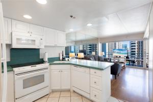 a kitchen with white cabinets and a living room at Ilikai Tower 1538 condo in Honolulu +14 photos