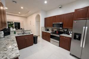 a kitchen with wooden cabinets and a stainless steel refrigerator at Peaceful Inn at Deerfield Beach Boca Raton in Deerfield Beach +6 photos