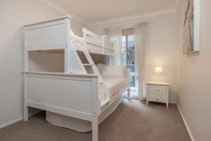 a bedroom with a white bunk bed and a window at Boo's Place in Blueys Beach