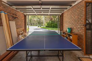 a ping pong table in a garage with a brick wall at Boo's Place in Blueys Beach
