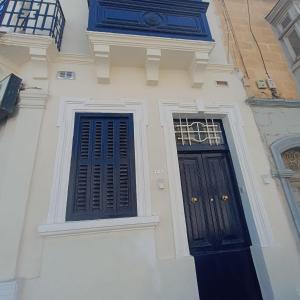 a building with two black doors and a window at Hypogeum SuiteStudio in Ħal Saflieni