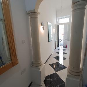 a hallway with white columns and a black and white tile floor at Hypogeum SuiteStudio in Ħal Saflieni +2 photos