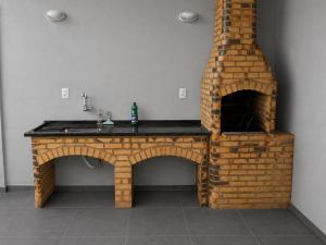 a kitchen with a brick fireplace next to a sink at Heyco camping e hospedaria in Cabo Frio