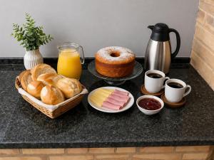 a table with bread and pastries and a jug of orange juice at Heyco camping e hospedaria in Cabo Frio