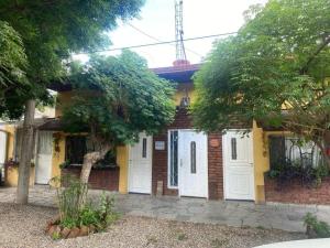 a brick building with white doors and a tree at BelDaMar in Capilla del Monte