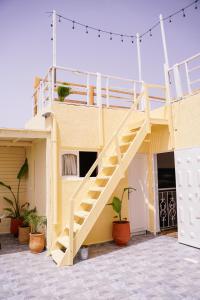 a yellow building with a staircase on it at Salty Life Surf House in Imsouane