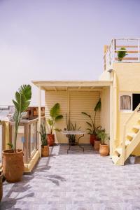 a patio with potted plants and a table on a building at Salty Life Surf House in Imsouane