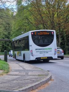 a white bus is driving down a street at Ipswich Town 3 Bed House in Copdock
