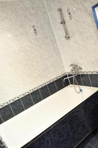 a bathroom with a white tub and black tiles at Apartments KSGM London at Gamarnika 6A in Khabarovsk