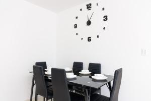 a black table with chairs and a clock on a wall at Apartamento 201 - a 5 minutos del centro de Pitalito in Pitalito