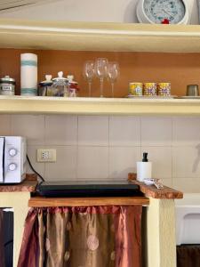 a kitchen with a counter with glasses on a shelf at NURAS - Gioberti Charme House in Alghero