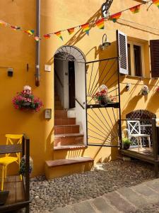 a yellow building with a door and flowers on it at NURAS - Gioberti Charme House in Alghero