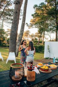 two women standing next to a picnic table with food at Casa com 4 quartos e Jardim Espaçoso - Santa Sofia in Moledo +28 photos