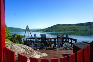 een houten terras met stoelen en een tafel op een meer bij Fjordside Lodge in Hordvik