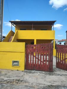 a yellow house with a red gate in front of it at Sobrado Frescor do Mar! in Cabo Frio