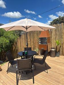 a table and chairs under an umbrella on a deck at Euetu na Lapinha da Serra in Santana do Riacho