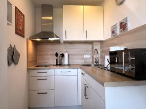 a kitchen with white cabinets and a black appliance at Tief 10 Neptun mit Internet 607 in Wangerland