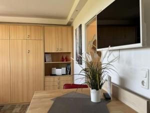 a kitchen with wooden cabinets and a table with a plant at Tief 10 Neptun mit Internet 607 in Wangerland