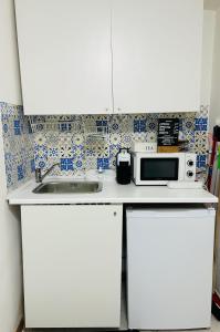 a white kitchen with a microwave and a sink at casa kiki in Pozzuoli
