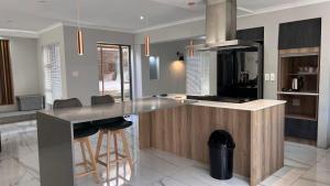 a kitchen with a island with bar stools in it at Cape one guest house in Welgelegen