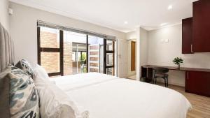 a bedroom with a large white bed and a desk at Cape one guest house in Welgelegen