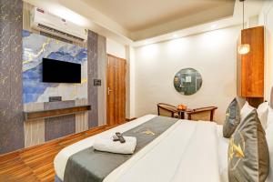 a bedroom with a bed with a tv on the wall at Hotel The Arrow International Laxmi Nagar in New Delhi