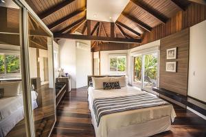 a bedroom with a large bed in a room with windows at Hospedaria das Brisas in Praia do Rosa