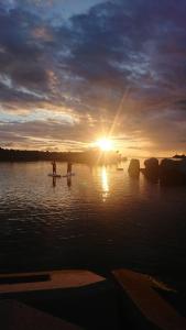 two people standing on a paddle board in the water at sunset at Harbor base SHARK in Sado +91 photos