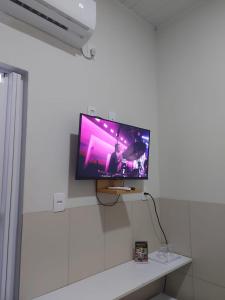 a flat screen tv hanging on a white wall at Mini suíte Atitude no coração de Maragogi in Maragogi +40 photos