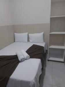 a bedroom with two beds and a book shelf at Mini suíte Atitude no coração de Maragogi in Maragogi