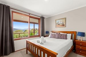 a bedroom with a bed and a large window at Winterwood 9 Camira Ave in Jindabyne