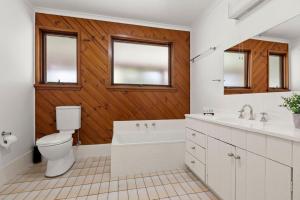 a bathroom with a toilet and a tub and a sink at Winterwood 9 Camira Ave in Jindabyne +13 photos