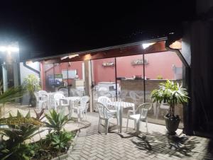 a patio with white chairs and tables in a restaurant at Pousada sushi-lazer in Casa Branca