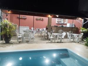 a patio with tables and chairs and a swimming pool at Pousada sushi-lazer in Casa Branca