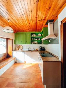 a kitchen with green cabinets and a wooden ceiling at Casa com 4 quartos e Jardim Espaçoso - Santa Sofia in Moledo