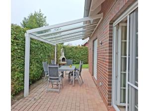 a pergola on a patio with a table and chairs at Deichhuus in Neßmersiel in Neßmersiel
