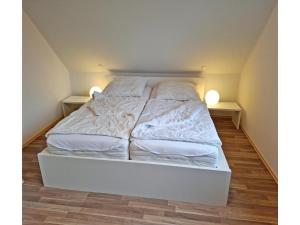 a white bed in a room with two lamps at Deichhuus in Neßmersiel in Neßmersiel