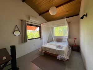 a bedroom with a bed with a mosquito net at Casa Gemini in Ilha de Boipeba