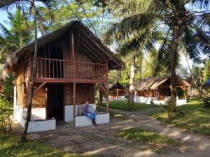 a person sitting on a couch in front of a house at MAHAMBO BEACH hôtel in Mahambo +18 photos