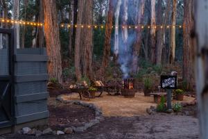 a patio with a table and a fire grill in a forest at The Duckling in Glenlyon