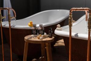 a bath tub with bottles of alcohol on a stool next to a bathtub at The Duckling in Glenlyon