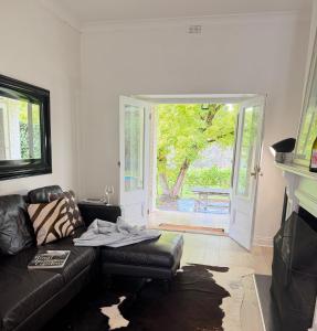 a living room with a black leather couch and an open door at Woodlands - Vineyard setting in Penwortham +30 photos
