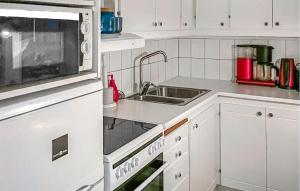 a white kitchen with a sink and a microwave at Amazing Home In Luleå With Sauna in Luleå