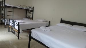 two beds in a room with white sheets at Casa Hotel la Alsacia in Santa Rosa de Cabal
