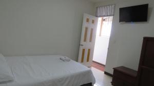 a bedroom with a bed and a flat screen tv at Casa Hotel la Alsacia in Santa Rosa de Cabal