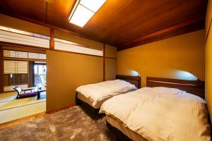 a bedroom with two beds and a table and a chair at Ryoutei Ryokan Yasui in Hikone