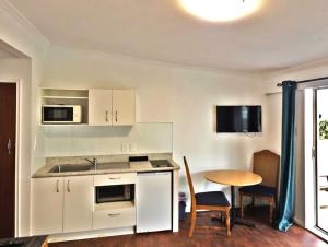 a kitchen with white cabinets and a table at Golden Aura Suites in Stratford