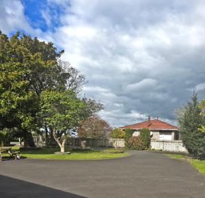 a road with a house and a fence and trees at Golden Aura Suites in Stratford