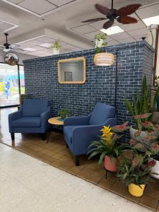 a lobby with two blue chairs and a tv on a brick wall at Central YMCA Residences in Honolulu